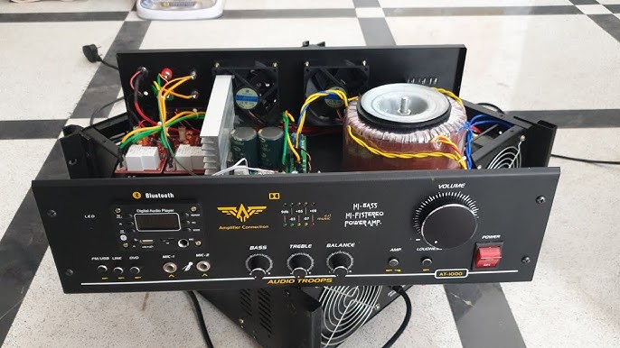 Open high-fidelity stereo power amplifier chassis showing a large toroidal power transformer, heat sink, capacitors, and internal wiring